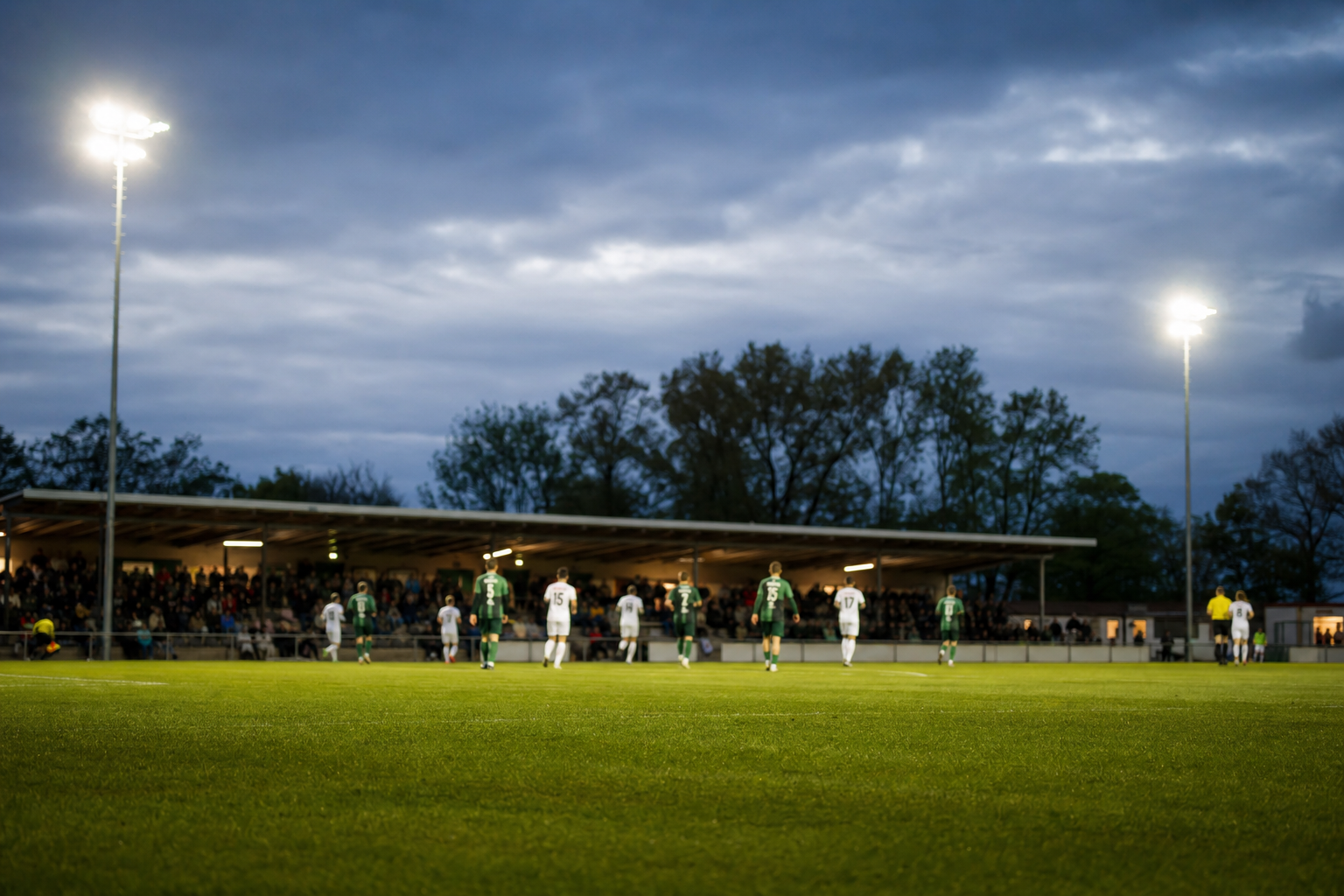 Flutlichtspiel in einem norddeutschen Fußballstadion am Abend mit Blick auf Rasen und Tribüne